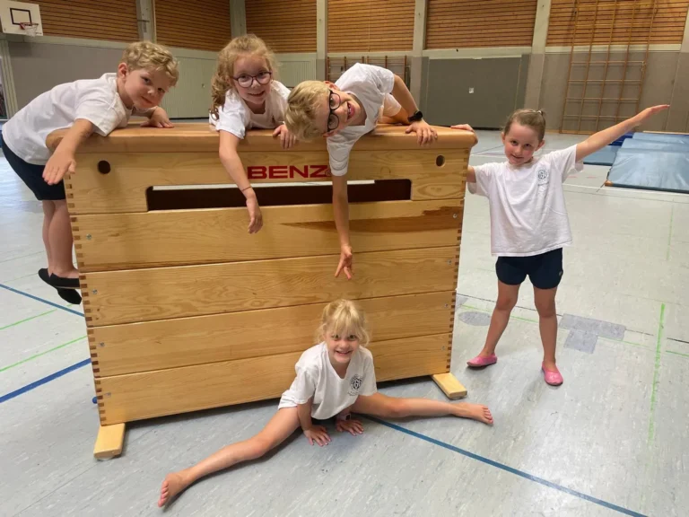 Fünf Kinder trainieren vor und auf einem Kasten.